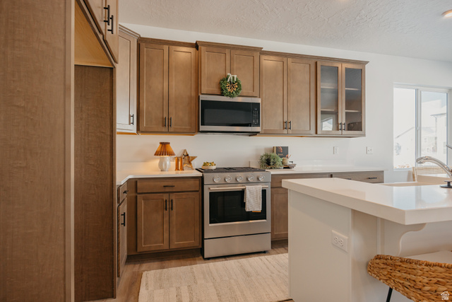4595 North Fallow Way, Unit 511 Eagle Mountain, UT 84005 - Photo 16 of 32 Kitchen with stainless steel appliances, a kitchen breakfast bar, two tone color scheme, glass insert cabinets, and light stone counters