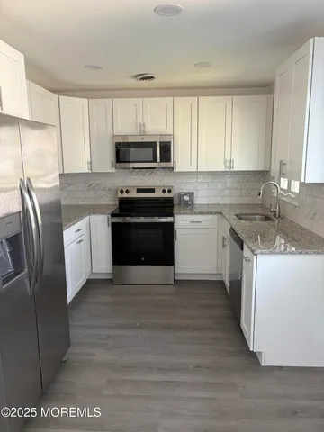 a kitchen with stainless steel appliances granite countertop a refrigerator a sink a stove a microwave and wooden cabinets