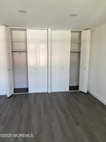 a view of an empty room with wooden floor and closet area