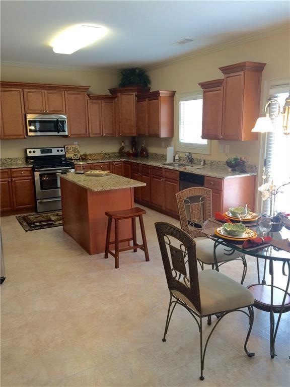 718 Channel Lane Lawrenceville, GA 30046 - Photo 11 of 16 a kitchen with stainless steel appliances kitchen island granite countertop a stove a sink a table and chairs