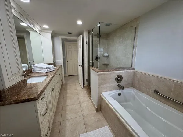 a bathroom with a granite countertop sink mirror and bathtub