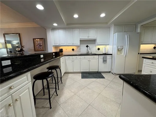 a kitchen with stainless steel appliances a sink a stove a refrigerator cabinets and chairs