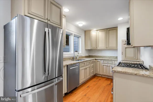 a kitchen with stainless steel appliances granite countertop a refrigerator a sink and a stove
