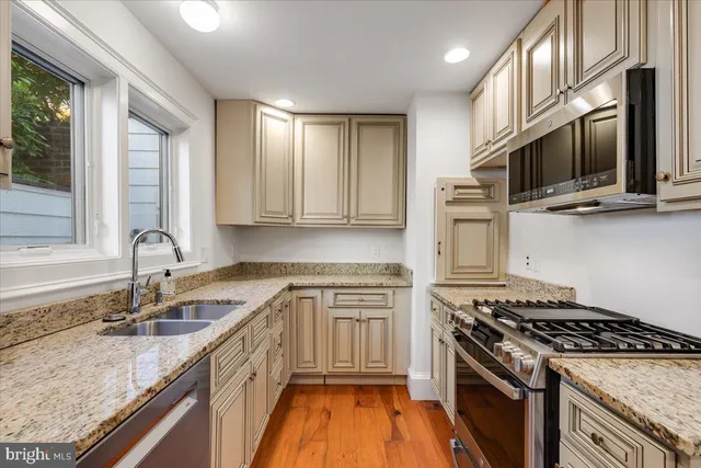 a kitchen with stainless steel appliances granite countertop a stove a sink and a microwave
