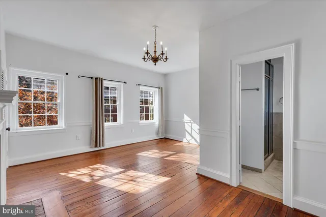 a view of an empty room with wooden floor fireplace and a window