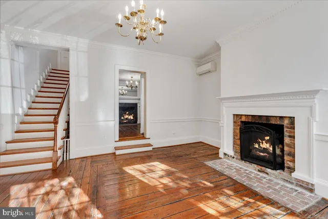a view of an empty room with wooden floor fireplace and a window