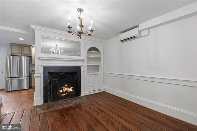 a view of a livingroom with a fireplace a chandelier and wooden floor