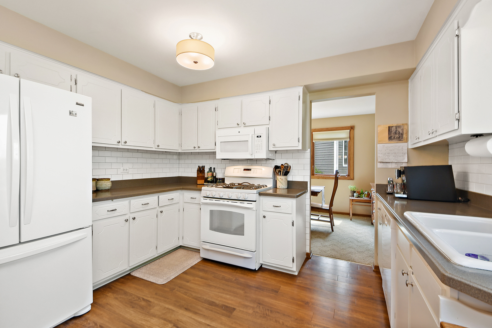 10918 3rd Street Mokena, IL 60448 - Photo 17 of 40 a kitchen with stainless steel appliances a stove a sink a refrigerator white cabinets and wooden floor
