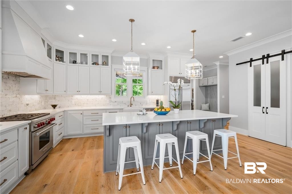 707 Cardamel Court Fairhope, AL 36532 - Photo 9 of 40 Kitchen featuring premium range hood, light hardwood / wood-style floors, appliances with stainless steel finishes, and a barn door