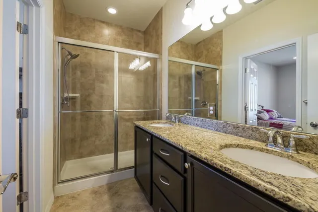 a bathroom with a granite countertop sink a mirror and a shower