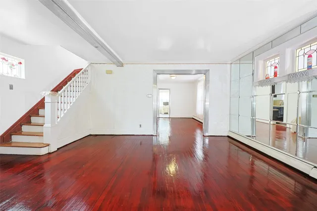 a view of an empty room with wooden floor and stairs