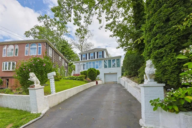 a view of a brick house with a yard plants and large trees