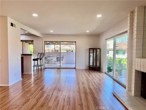 a view of an empty room with wooden floor and a bathroom