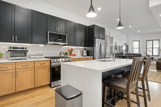 a kitchen with kitchen island granite countertop a stove a sink a oven a kitchen island with chairs and cabinets