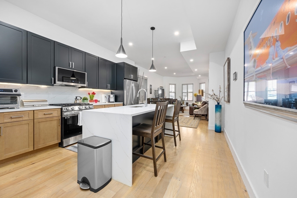 231 Everett Street, Unit 1 Boston, MA 02128 - Photo 18 of 39 a kitchen with a table chairs refrigerator and microwave