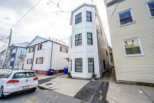 a view of a white building among the cars parked in front of a house