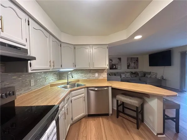 a kitchen with stainless steel appliances granite countertop a sink a stove top oven a counter space and cabinets