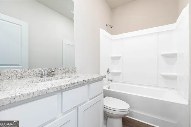 a bathroom with a granite countertop sink a toilet and bathtub