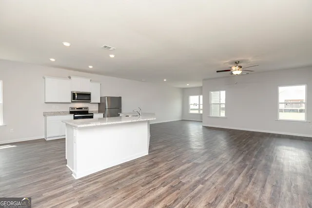 a view of kitchen with microwave a refrigerator and wooden floor