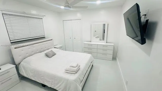 a bedroom with a bed a mirror and flat screen tv
