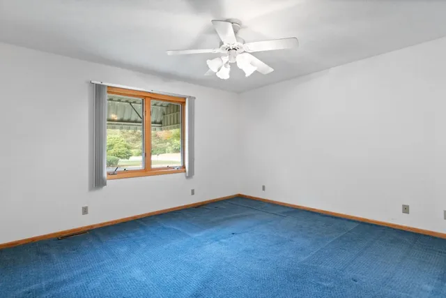 an empty room with chandelier fan and windows