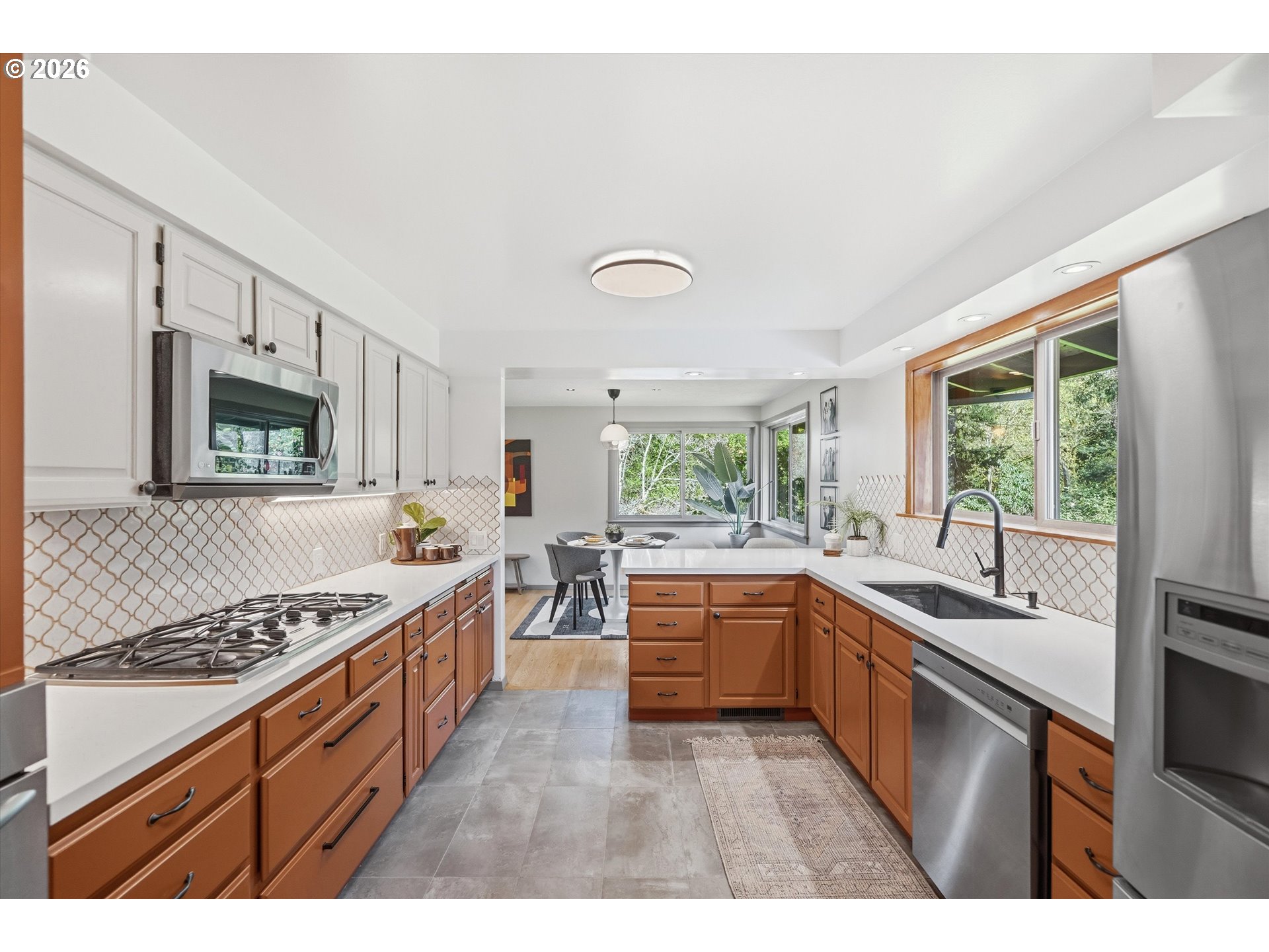 12802 Southeast Knapp Street Portland, OR 97236 - Photo 16 of 48 a kitchen with stainless steel appliances granite countertop a stove a sink dishwasher and white cabinets with wooden floor