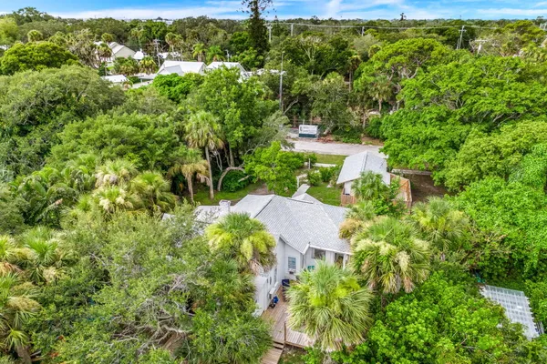 an aerial view of residential house with outdoor space and trees all around