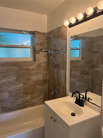 a bathroom with a sink and mirror with bathtub