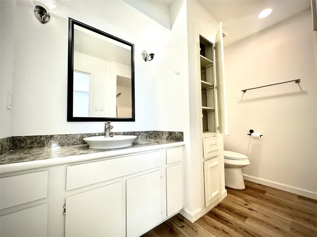 a bathroom with a granite countertop sink toilet and mirror