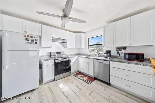 a kitchen with granite countertop a refrigerator stove top oven and sink