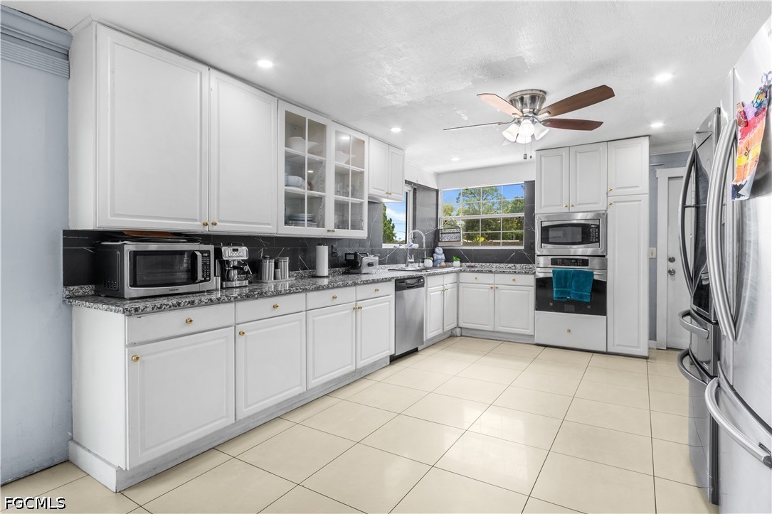 18 Illinois Road Lehigh Acres, FL 33936 - Photo 16 of 45 a kitchen with stainless steel appliances granite countertop a stove sink and cabinets