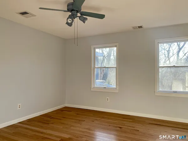 a view of an empty room with wooden floor and a window