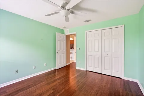 an empty room with wooden floor closet fan and windows