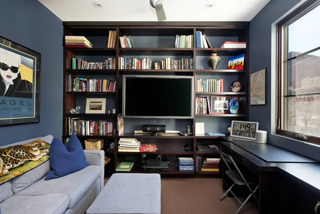 a living room with furniture a book shelf and a window
