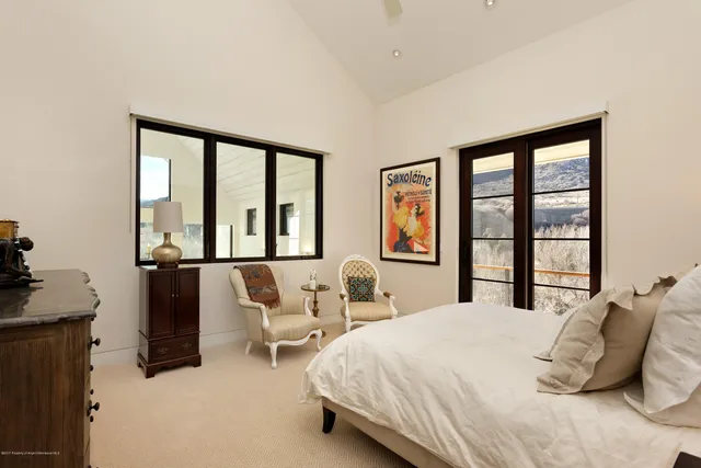 a bedroom with bed and large windows