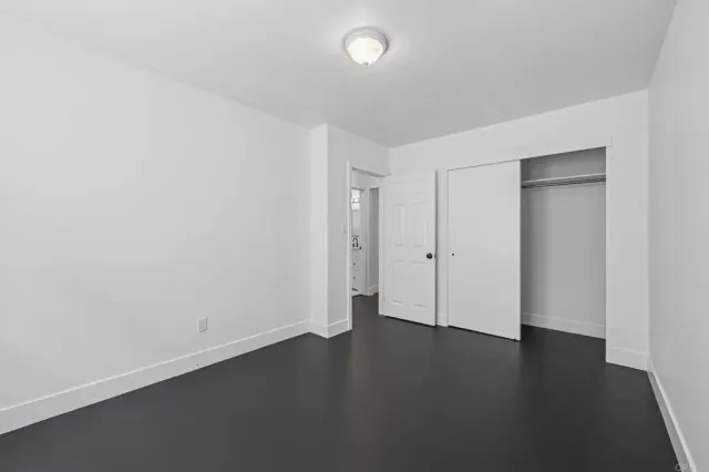 an empty room with wooden floor and white walls