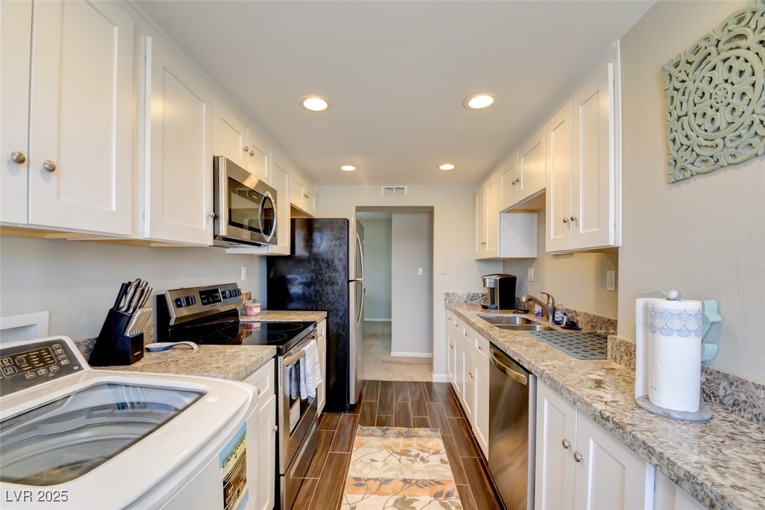 745 North Royal Crest Circle, Unit 127 Las Vegas, NV 89169 - Photo 13 of 26 Kitchen with stainless steel appliances, washer / dryer, a sink, white cabinets, and wood tiled floors