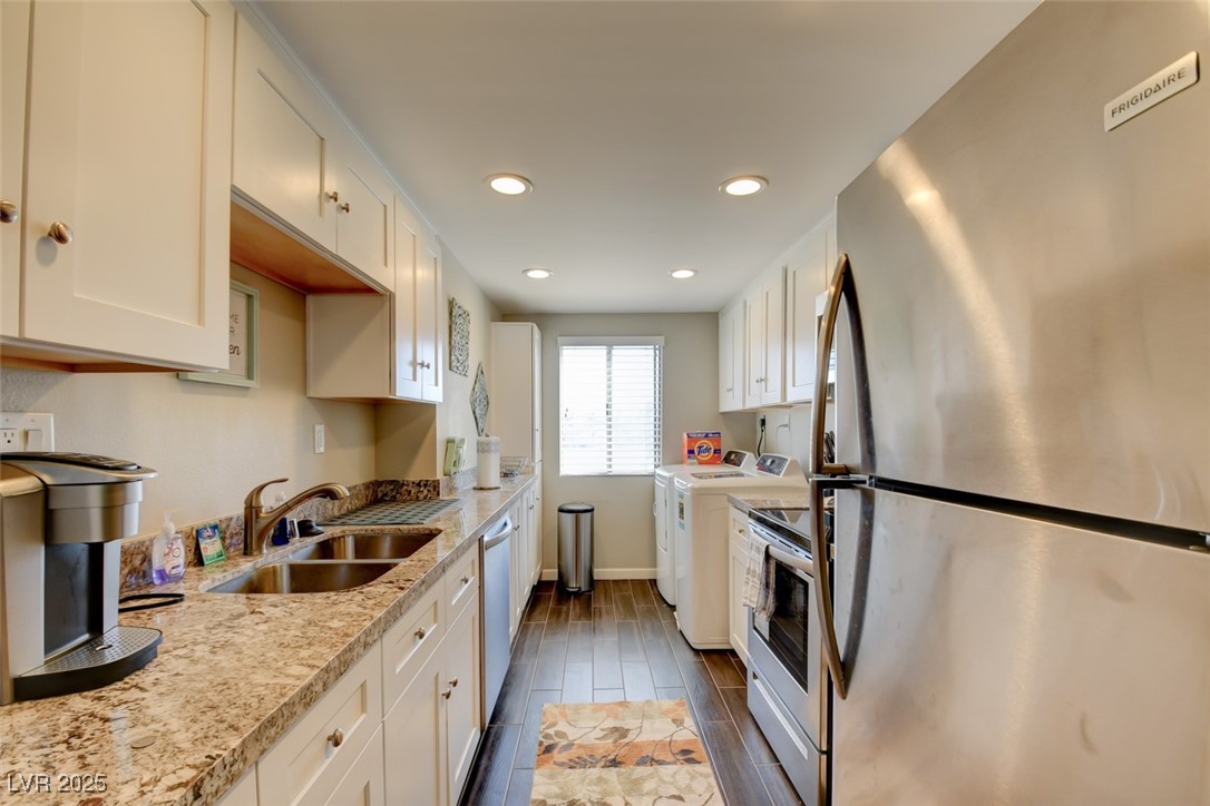 745 North Royal Crest Circle, Unit 127 Las Vegas, NV 89169 - Photo 16 of 26 Kitchen featuring stainless steel appliances, washer and dryer, a sink, white cabinetry, and baseboards