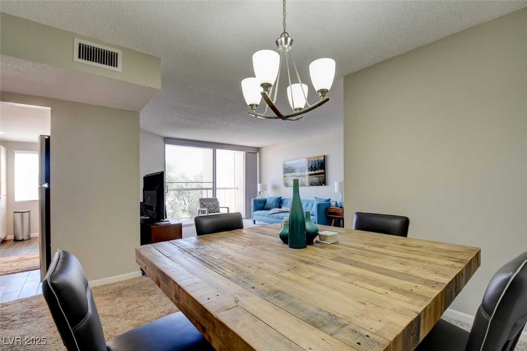 745 North Royal Crest Circle, Unit 127 Las Vegas, NV 89169 - Photo 18 of 26 Dining room featuring a chandelier, baseboards, and a textured ceiling