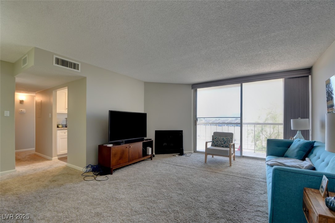 745 North Royal Crest Circle, Unit 127 Las Vegas, NV 89169 - Photo 19 of 26 Carpeted living room featuring a textured ceiling and baseboards