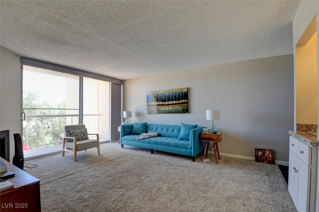 745 North Royal Crest Circle, Unit 127 Las Vegas, NV 89169 - Photo 20 of 26 Carpeted living area featuring plenty of natural light, a textured ceiling, and floor to ceiling windows