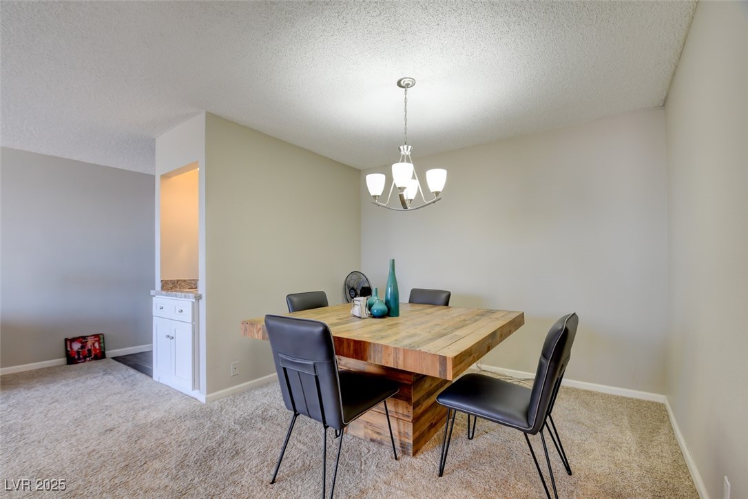 745 North Royal Crest Circle, Unit 127 Las Vegas, NV 89169 - Photo 21 of 26 Dining room featuring a chandelier, light colored carpet, a textured ceiling, and baseboards