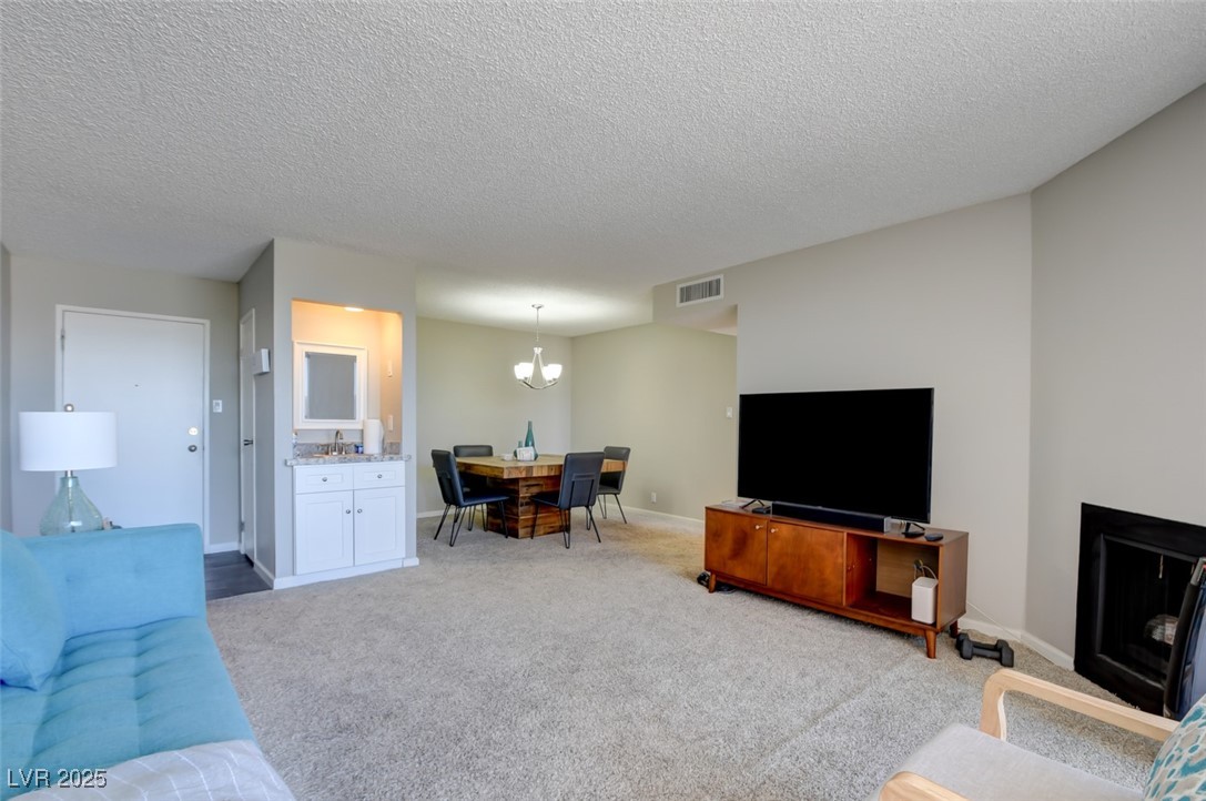 745 North Royal Crest Circle, Unit 127 Las Vegas, NV 89169 - Photo 22 of 26 Carpeted living area featuring a textured ceiling, baseboards, and a chandelier