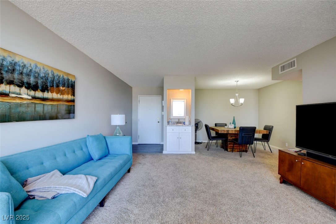 745 North Royal Crest Circle, Unit 127 Las Vegas, NV 89169 - Photo 23 of 26 Living area featuring a chandelier, light colored carpet, and a textured ceiling