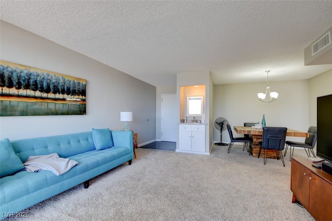 745 North Royal Crest Circle, Unit 127 Las Vegas, NV 89169 - Photo 24 of 26 Living area featuring a chandelier, light colored carpet, a textured ceiling, and baseboards