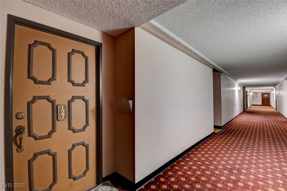 745 North Royal Crest Circle, Unit 127 Las Vegas, NV 89169 - Photo 4 of 26 Hallway with a textured ceiling, carpet flooring, and baseboards