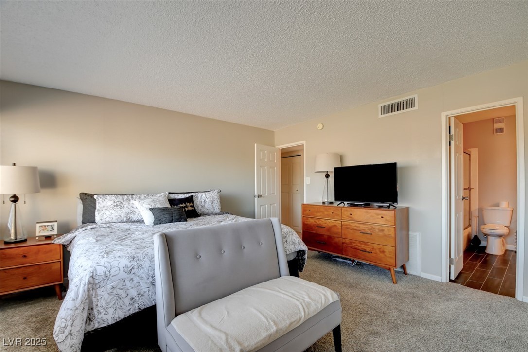 745 North Royal Crest Circle, Unit 127 Las Vegas, NV 89169 - Photo 9 of 26 Bedroom featuring carpet flooring, a textured ceiling, and ensuite bathroom