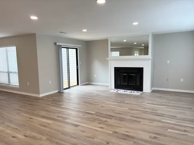 an empty room with wooden floor fireplace and windows