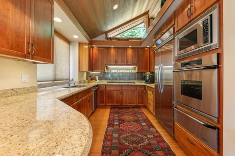 a kitchen with stainless steel appliances granite countertop a stove a sink and a microwave