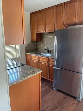 a kitchen with stainless steel appliances granite countertop a refrigerator a sink dishwasher a stove with wooden cabinets